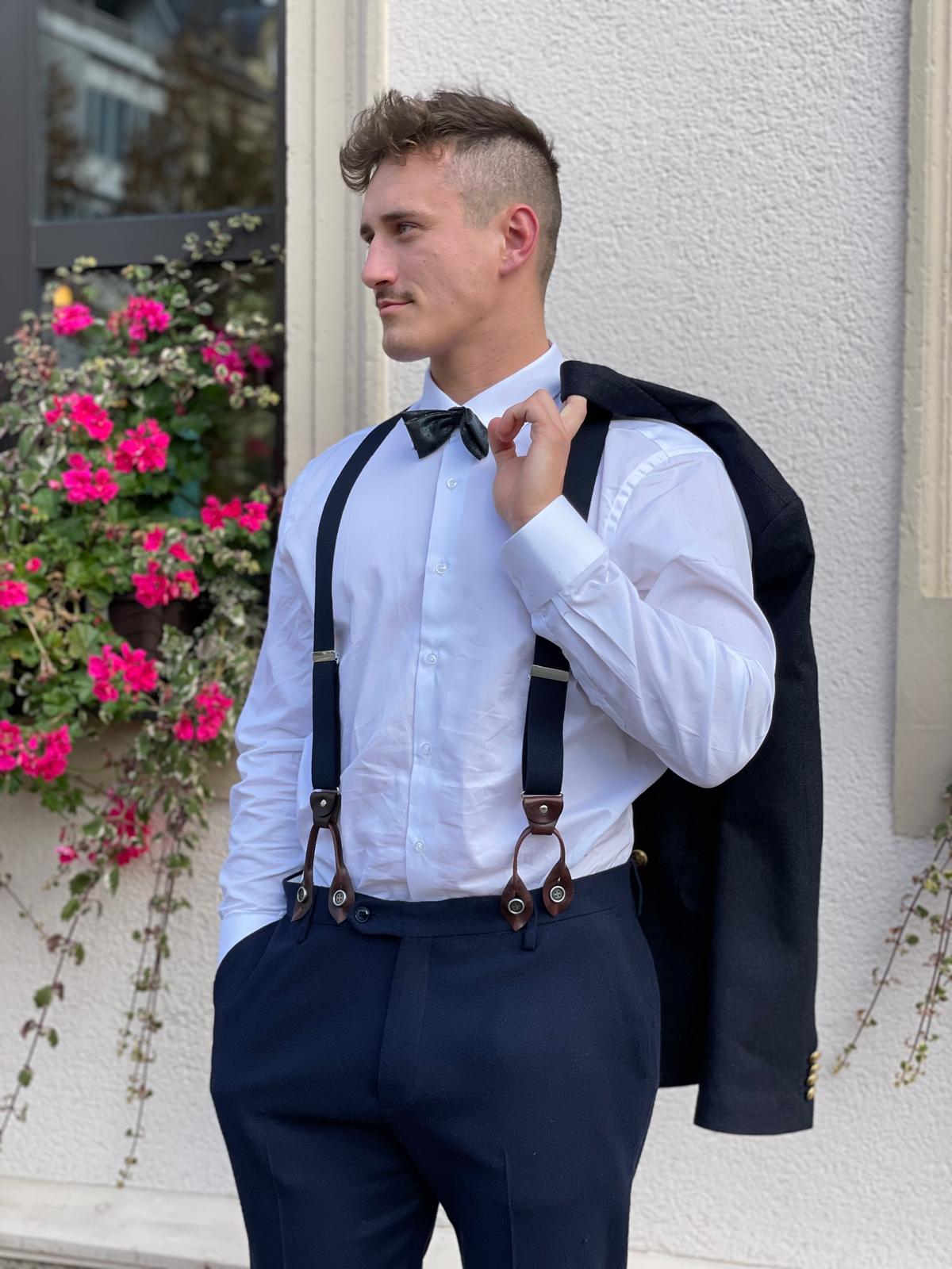 Ein junger Mann mit lockigem Haar und Fliege steht lässig neben pinken Blumen